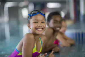 young black girl smiling at the pool with goggles on her head