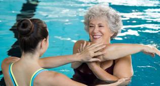Trainer helping woman stretch in pool